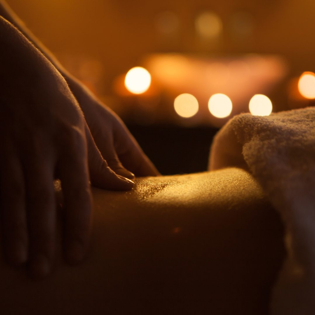 hand massage of back with oil. burning candles on background near sink